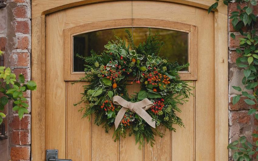 rose hip wreath hung on a wooden door