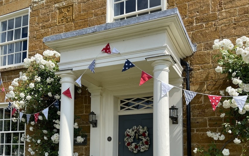 Iceberg climbing rose up a wall with royal bunting.