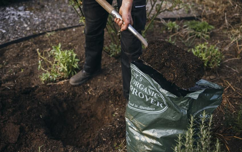 Man using a shovel to place soil improver on the ground