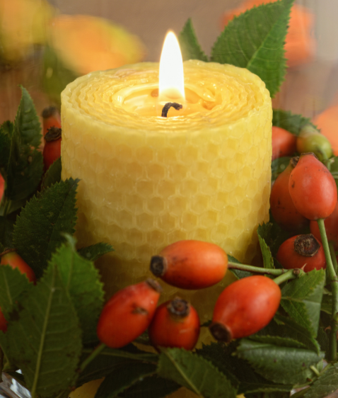 Candle burning with rose hips around it